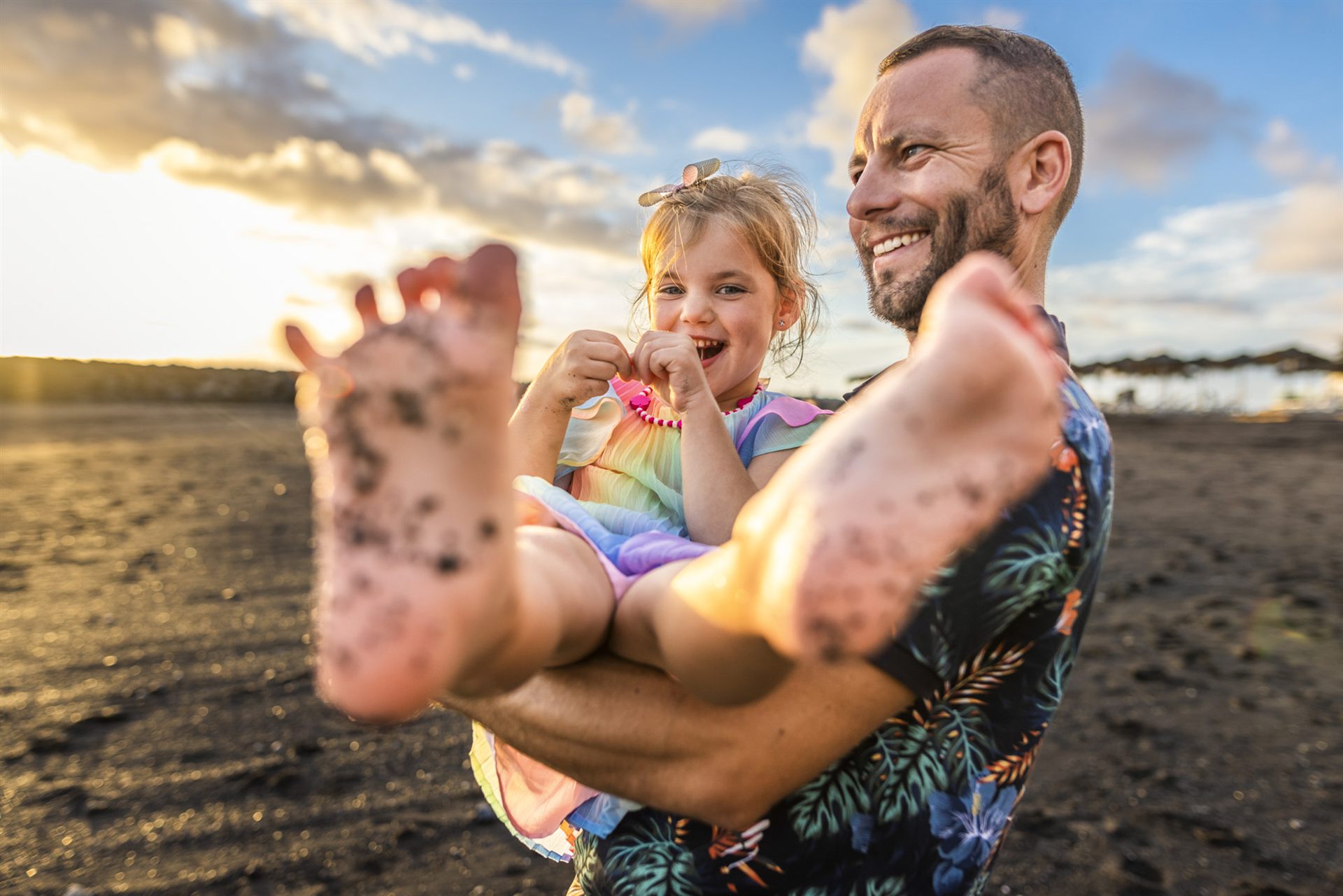 Father and daughter having fun in the sand on Playa del Duque